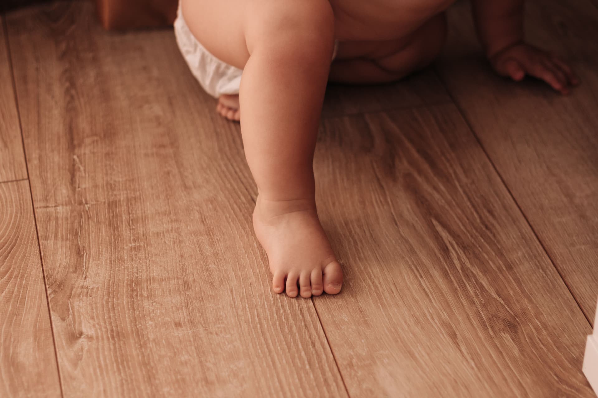 A baby crawling on a hardwood floor