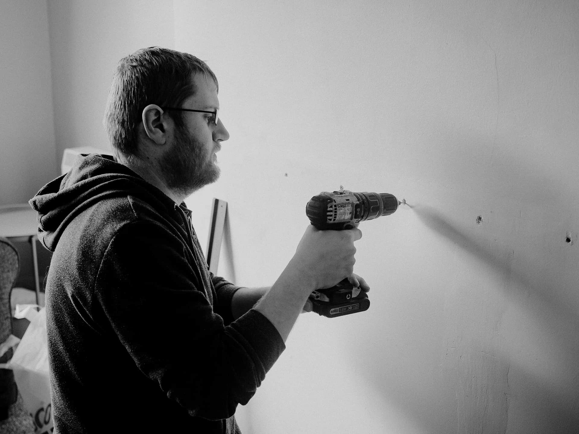 A person using a cordless drill on a wall
