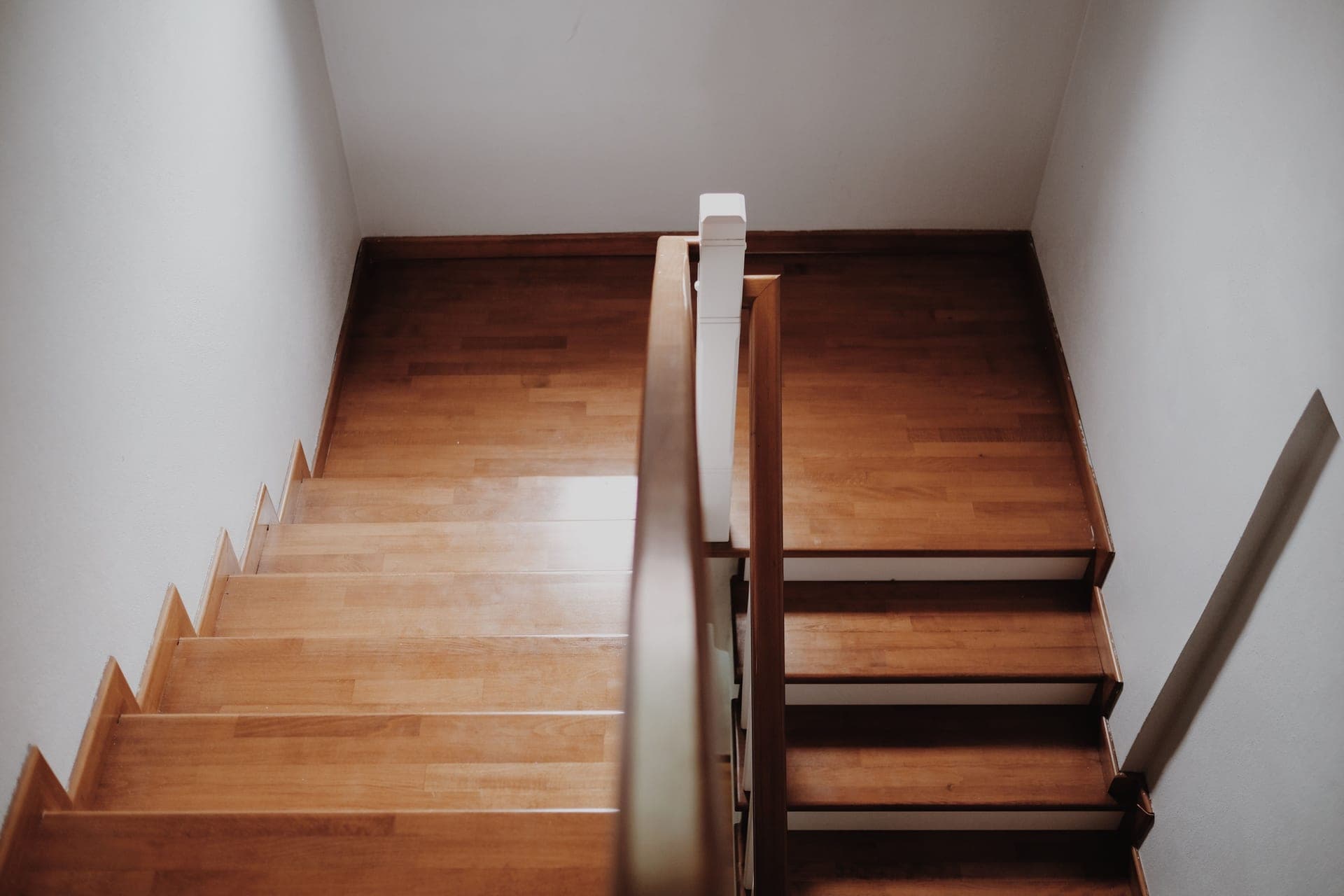 The bottom of a wooden staircase with a banister