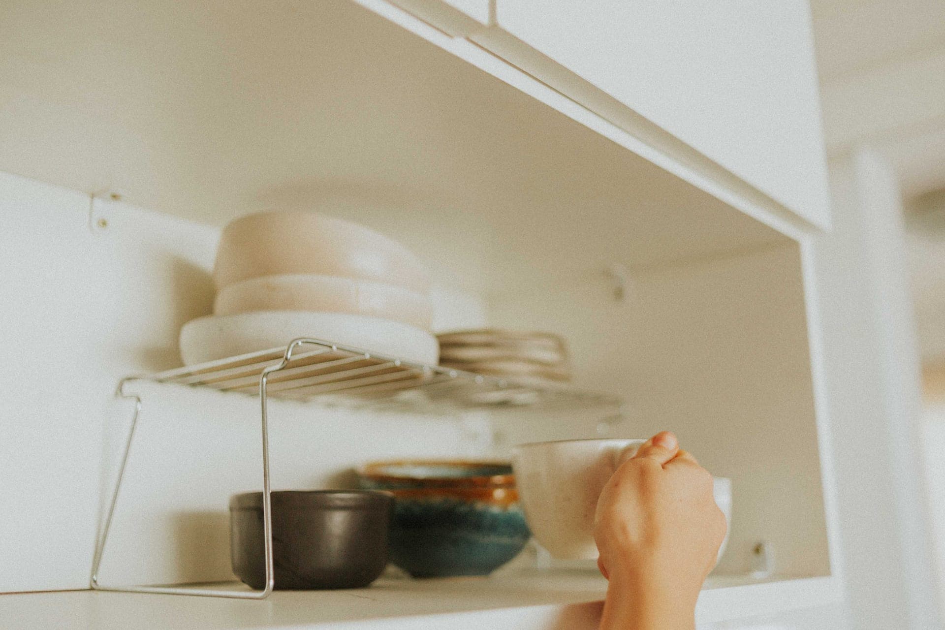 A toddler reaching for the handle of a low kitchen cabinet