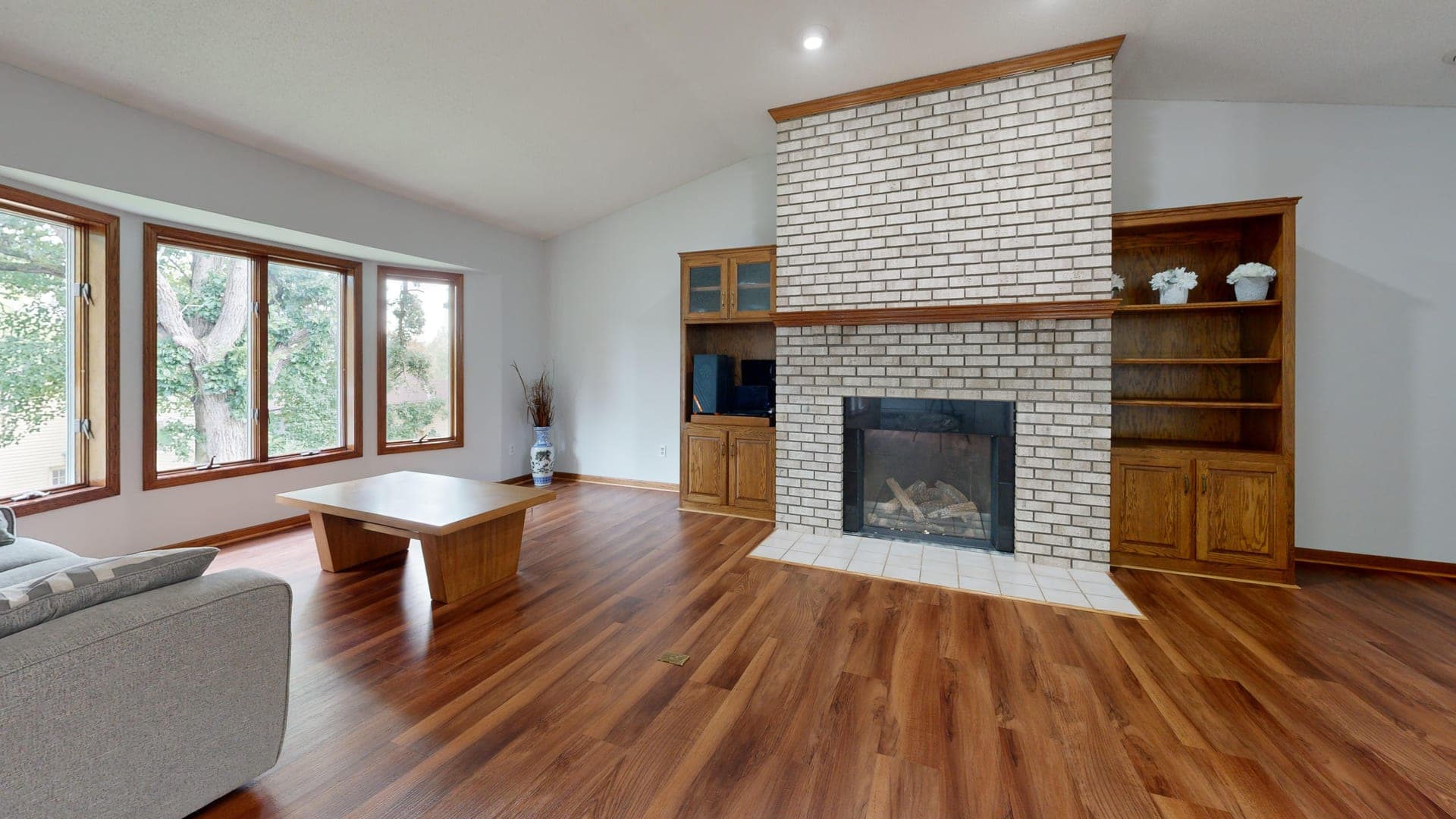 A living room with a brick fireplace and a large window